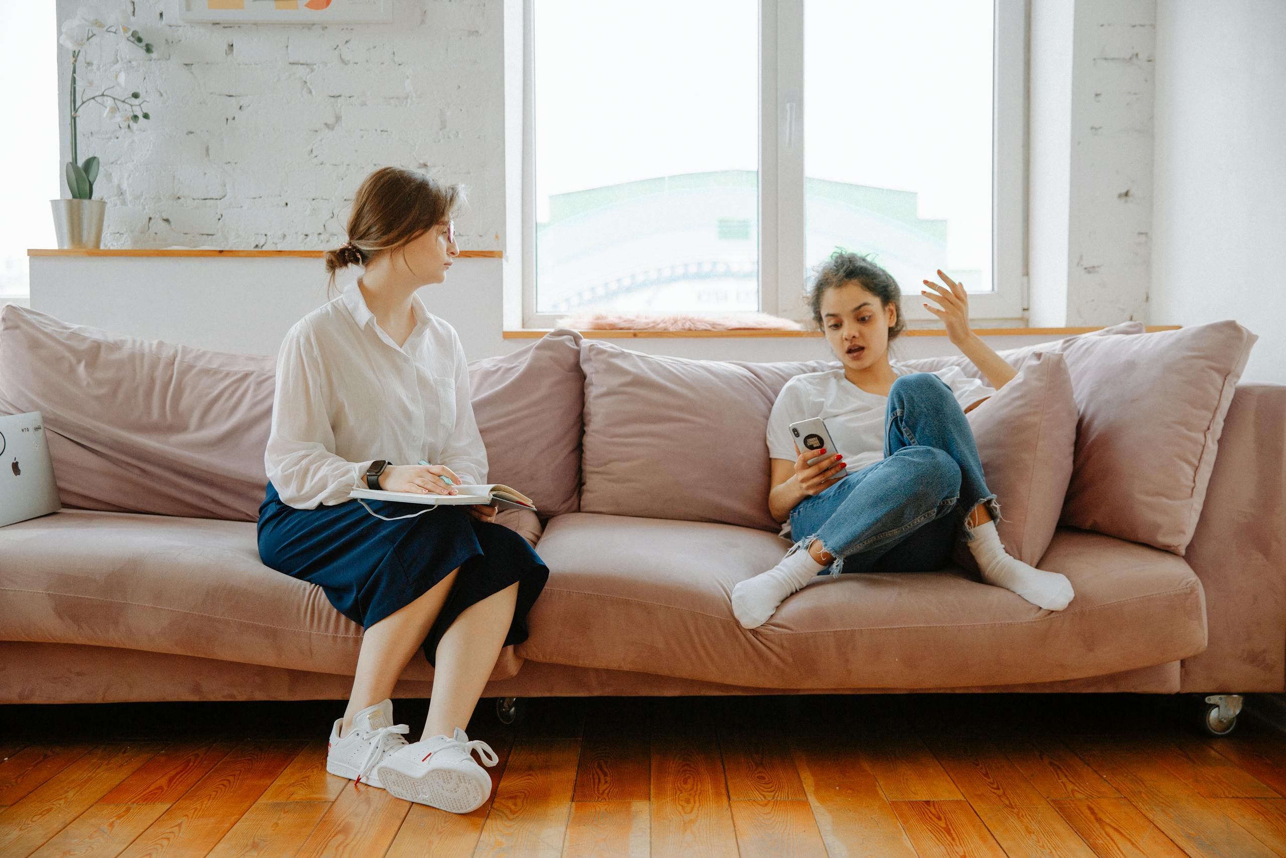 A therapist and a teenager engage in a counseling session on a comfortable sofa.